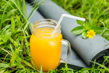 Fresh  orange juice and yoga mat on the grass