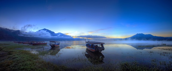Boats wait for passengers. View of boats leaning on the lake in the early of the dawn in kintamani lake bali - obrazy, fototapety, plakaty