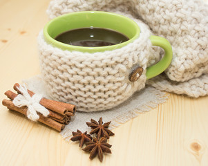 Obraz na płótnie Canvas A cup of coffee in a knitted cover with spices