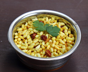Bhel poori, an Indian road side snack in a container on a moody background.