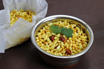 Bhel poori, an Indian road side snack in a container on a moody background.