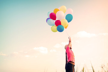 Happy young woman with colorful balloons, enjoy in the morning time at grassland. concept of birthday party, wedding and honeymoon in summer - vintage color tone effect