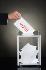Businessperson Hand Putting Vote Into A Ballot Box
