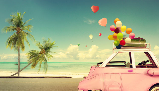 Vintage pink classic car with heart colorful balloon on beach blue sky - concept of love in summer and wedding. Honeymoon trip