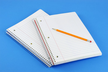 blank notebook with pencil on blue background