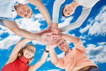 Happy Friends Stacking Hands Against Sky