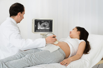 Doctor Performing Ultrasound Scan On Expecting Woman