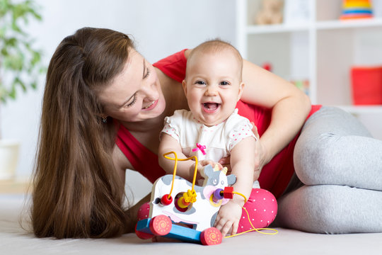 Mother and baby girl playing with toy in living room