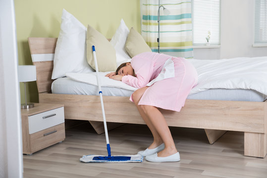 Tired Female Housekeeper Lying On Bed