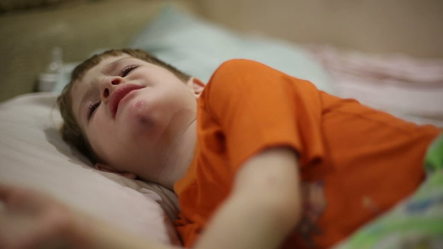 The boy was injured chin, he's got a big bruise, he lies on the bed and tolerate the pain
