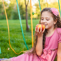 girl eating an apple in a summer park sitting on a plaid