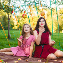 Mom and daughter in the park posing with apples in their hands