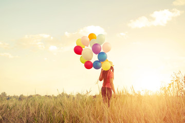 Happiness teen girl with colorful balloons enjoy in the sundown time at grassland. Happy birthday...