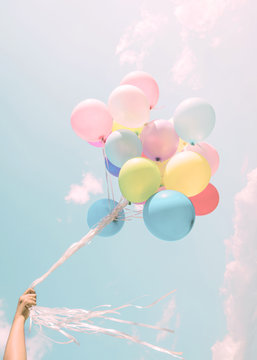 Fototapeta Girl hand holding colorful balloons. happy birthday party. vintage pastel filter effect