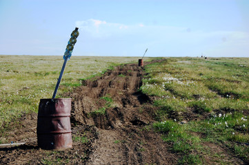 Old oil drum with road mark stake at tundra