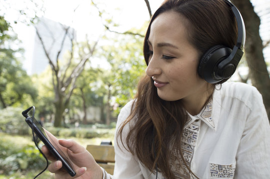 Asian women are listening to music in the park bench