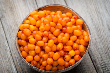 Buckthorn berry basket on wooden background.