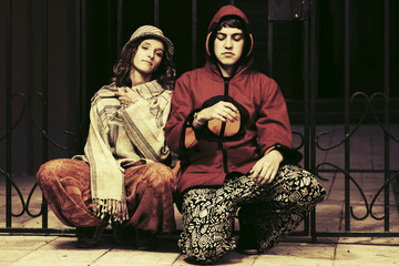 Fototapeta na wymiar Young fashion hippie couple sitting against an iron fence