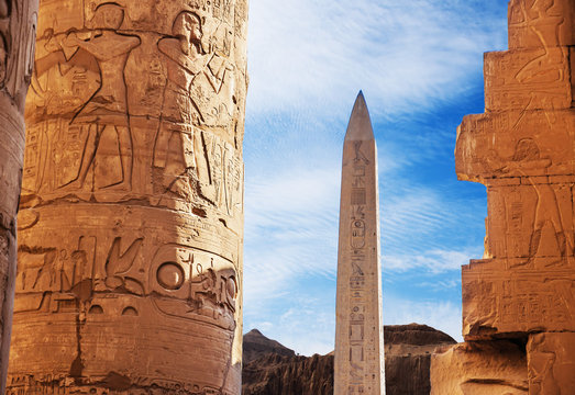 Ancient ruins of Karnak temple in Egypt in the summer, Obelix and statues of Ramses II at the first pylon of the Luxor Temple (1279-1213 BC)