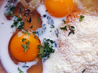 ingredients for a traditional Italian frittata in a bowl: eggs, herbs, milk, Parmesan cheese, onions.