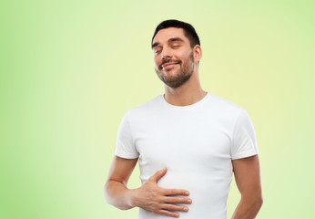 happy full man touching tummy over green 