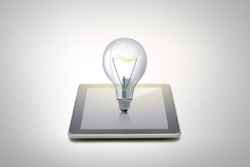 close up of tablet pc computer with light bulb