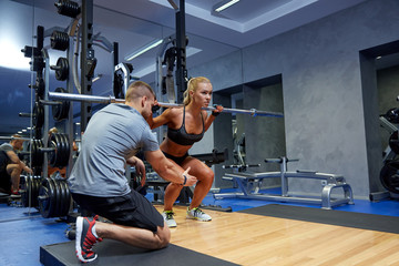 man and woman with bar flexing muscles in gym