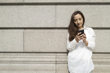 Women are using a smart phone in front of the wall