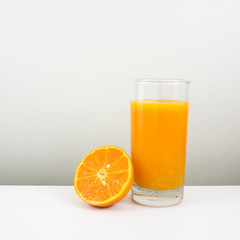 The glass of tasty pure orange juice and fresh orange half for a good healthy.