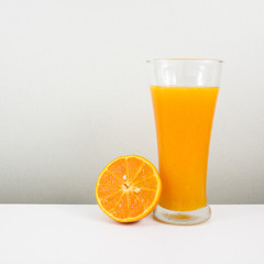 The glass of tasty pure orange juice and fresh orange half for a good healthy.