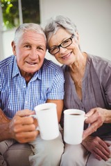 Senior couple having coffee in living room