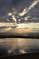 Baltic sea. Golden sunset on the sea. Coastal landscape with setting Sun reflections on the water and sand
