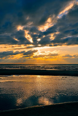 Baltic sea. Golden sunset on the sea. Coastal landscape with setting Sun reflections on the water and sand