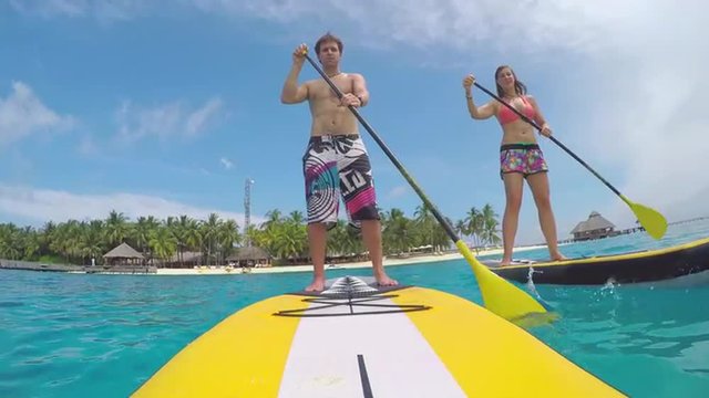 Young couple SUP boarding in exotic Maldives