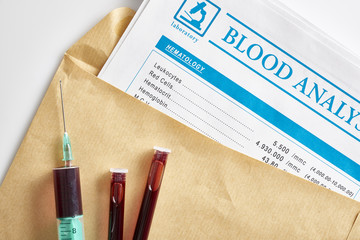 Blood report in envelope with vials and syringe with blood