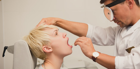 Doctor ENT checking ear with otoscope to woman patient