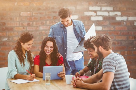 Composite image of creative business team gathered around a table