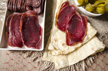 Thin bread with slices dried salted beef coated spices 
