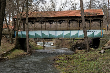 Covered bridge over the river with a small waterfall