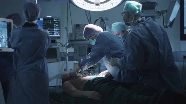 Medical Team Performing Defibrillation in Modern Operating Room. Shot on RED Cinema Camera.