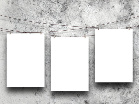 Close-up of three hanged paper sheet with pegs on weathered concrete wall background