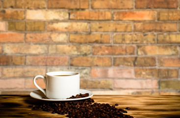 Coffee beans and coffee in white cup on wooden table opposite a