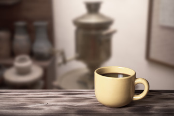 Coffee in a cup on wooden table opposite a defocused the interio