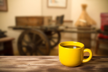 Coffee in a cup on wooden table opposite a defocused the interio