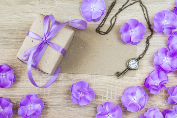 Gift box, purple flowers, key-shaped clock and blank paper card