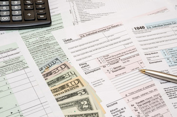 1040 tax form  with pen, dollar and calculator