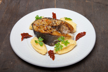Fried tuna fish with mashed potato, dried tomato and parsley on