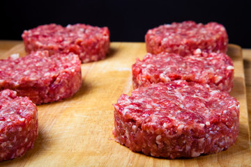 Raw cutlet of minced meat on a wooden cutting board. Shallow dep