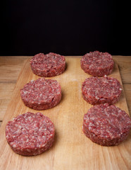 Raw cutlet of minced meat on a wooden cutting board