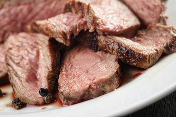 sliced beef steak on white plate close up